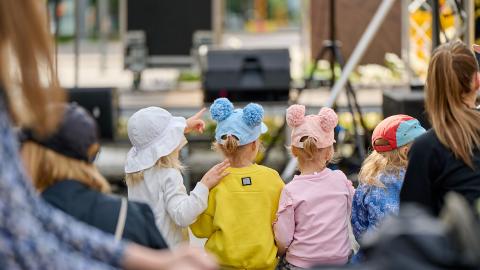 Kolme lasta katsomassa lavaohjelmaa Puistofiesta-tapahtumassa.