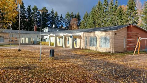 Keltainen rakennus, taustalla metsää.