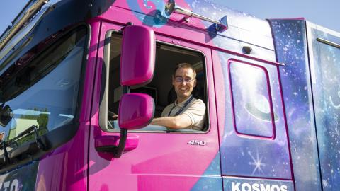 A driver looks out of a purple truck.