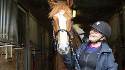 Sari Maunula is at the stables holding onto horse&#039;s halter.