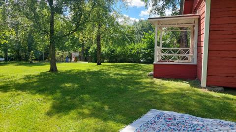 Punainen rakennus ja viltti nurmikolla.