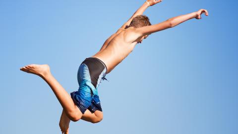 Henkilö uimahousuissa hyppäämässä ilmassa.