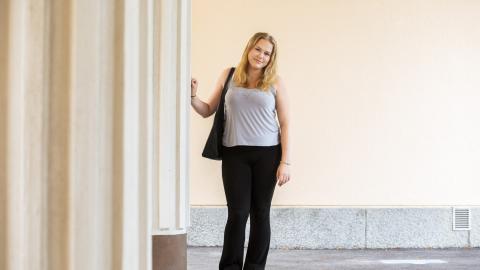 Nainen nojaa vasemmalla puolellaan olevaan pylvääseen.