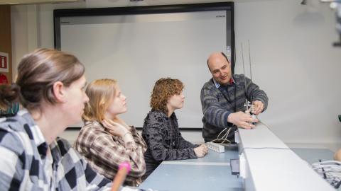 Three persons follow when one shows them the function of on technical item on board.