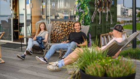 Kolme nuorta ihmistä kesällä istuskelemassa Ranta-Tampellassa kioskin edessä. 