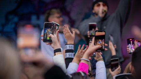 Käsiä, joissa puhelimet, jotka kuvaavat keikkaa. 