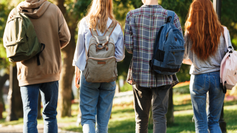 Neljä nuorta henkilöä kävelee rivissä reput selissään