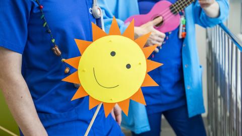 Siniseen paitaan pukeutunut henkilö pitelee auringon muotoista viiriä.