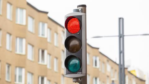 Liikennevalot, taustalla ruskea kerrostalo.