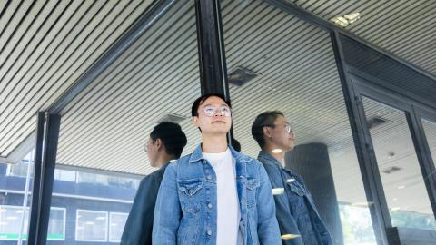 A person depicted as reflected from a glass wall in triplicate.