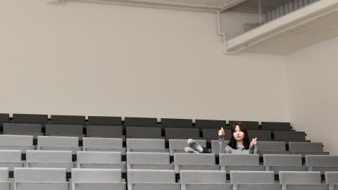 Henkilö istuu auditoriossa.