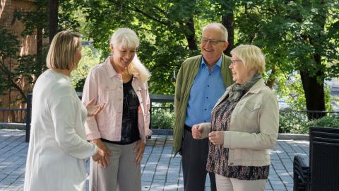 Neljä eläkeiän saavuttanutta tamperelaista keskustelee keskenään iloisesti hymyillen.