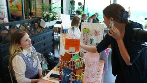 Livia Jokinen myy koruja ständillä. Asiakas kokeilee korvakoruja.