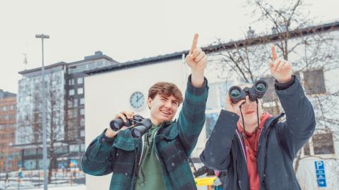 Klassillisen lukion opiskelijoita havainnoimassa koulun pihapiiriä kiikarein