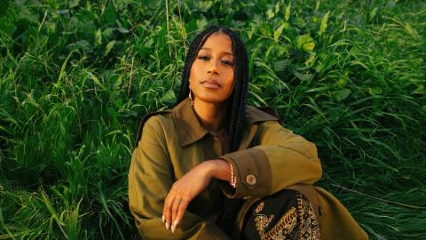 A woman sitting in front of grass.