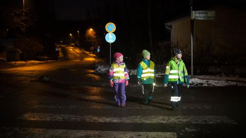 Lapset ylittämässä suojatietä heijastinliivit päällään.