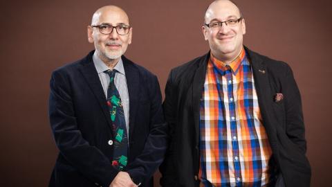 Kaksi siististi pukeutunutta keski-ikäistä miestä katsovat kameraan.