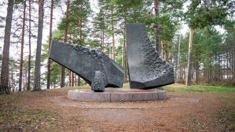 Puiden keskellä on kolme suurta metallilohkaretta.
