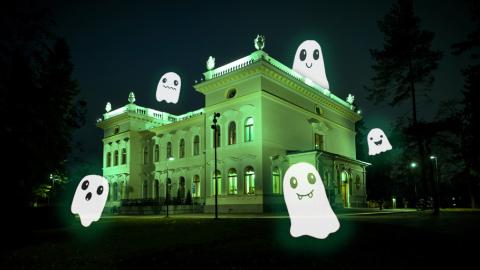 Vihreäksi valaistu Milavida kuvattuna ulkoa pimeällä. Rakennuksen ympärillä piirrettyjä kummituksia.