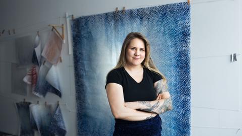 Nuori nainen seisoon sinisävyisen teoksen edessä. 