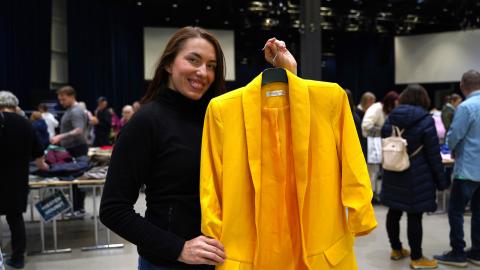 Nainen esittelee keltaista jakkua vaatteidenvaihtotapahtumassa.