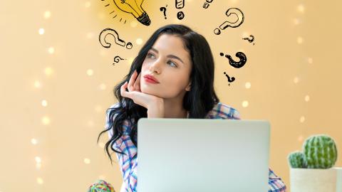 Henkilö istumassa tietokoneen ääressä. Hänen pään yläpuolelle on piirretty kysymysmerkkejä ja yksi hehkulamppu.