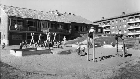 Mustavalkoisessa kuvassa Kalevan lastentalon pihamaan leikkialuetta, jossa muun muassa hiekkalaatikko ja kiipeilyteline.