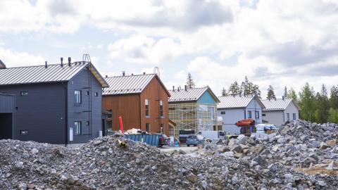 Rivistö rakennusvaiheessa olevia eri värisiä omakotitaloja, joiden pihamaalla kiviröykkiöitä.