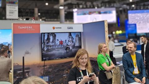 Ihmisiä seisoo messuosastolla. 