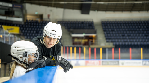 Äiti ja tytär katsovat toisiaan luistelukentän laidalla Hakametsän hallissa.
