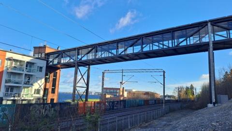 Santalahden katettu ja lasitettu kävelysilta ja hissitorni.