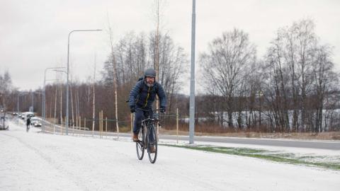 Pyöräilijä pyöräilemässä pyörätiellä talvella.