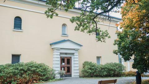 Keltainen vanha rakennus vehreässä ympäristössä.