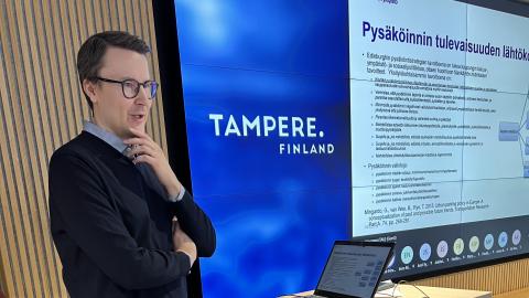 Henkilö seisoo ja kertoo tutkimuksesta seminaarissa.