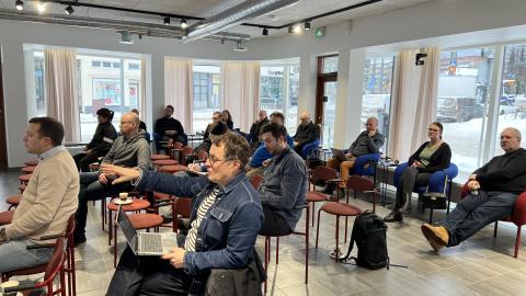 Henkilöitä istumassa kokoustilassa.