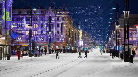 Ihmiset ylittävät lumista Hämeenkatua. Taustalla valaistuja rakennuksia.