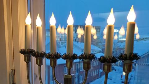 Seitsenhaarainen joulukynttelikkö ikkunalla.