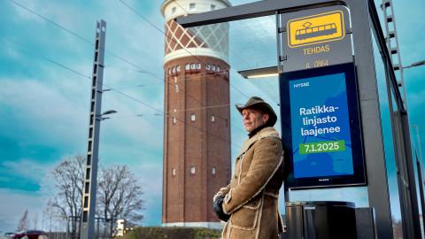 Cowboy-hattuinen mies odottaa ratikkaa Tehtaan pysäkillä Hiedanrannassa.