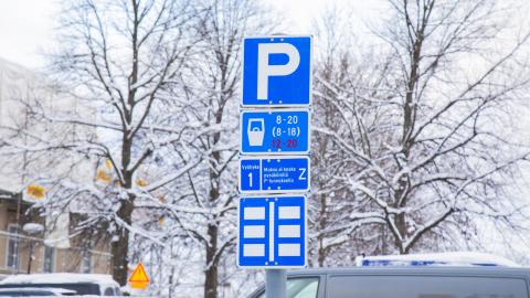 Kuvassa talvinen maisema, lumisia puita, autojen kattoja ja P-merkki Keskustorilla.