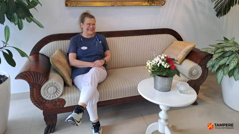 Henkilö istuu biedermeier-sohvalla ja etualalla on pyöreä pöytä, jonka päällä on kukkaruukku.