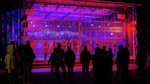 The choirs of the Cultural Cooperative Uulu hanging from the Laikunlava stage's net gate in a blue-red lighting in performance called Urban Cathedral.
