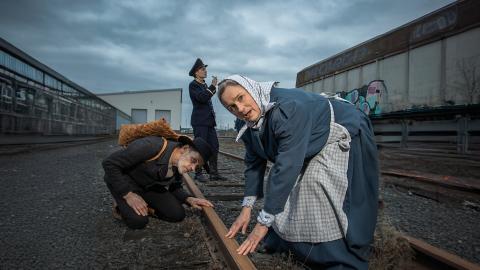 Rautatie-näytelmän hahmot ihmettelevät junaraiteita.