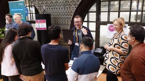 Englanninkielisen asukasillan osallistujia kokoontuneena pöydän ääreen keskustelemaan kaupungin edustajien kanssa.