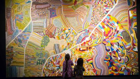 Kaksi lasta katselee isoa ja värikästä maalausta.