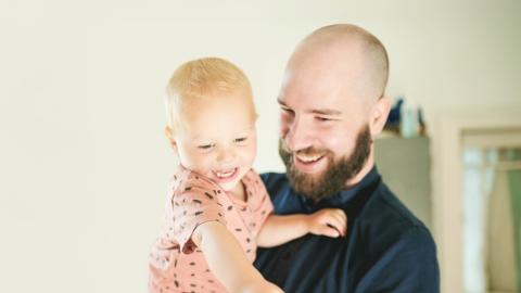 Isä pitää lasta sylissä.