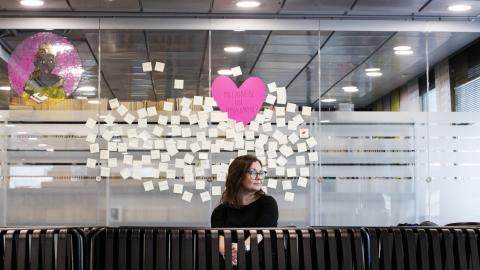 nainen keskellä kuvaa, taustalla lappuja.