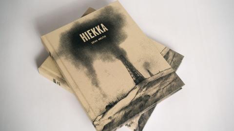 Eeva Meltion Hiekka-sarjakuva-albumeita kasassa. Kirjassa ruskean-musta kansi.