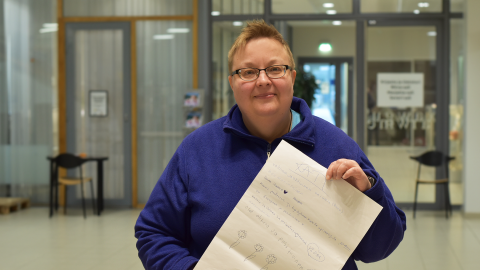 A person is standing in the lobby. They are holding a poster.