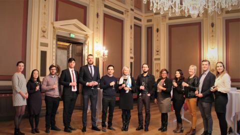 A group of people standing in a row in a stylish environment with wine glasses in their hands.