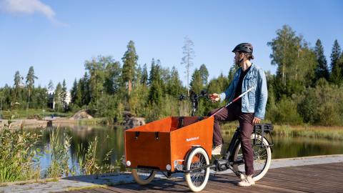 Henkilö tavarapyörän kanssa, katselee lammelle.